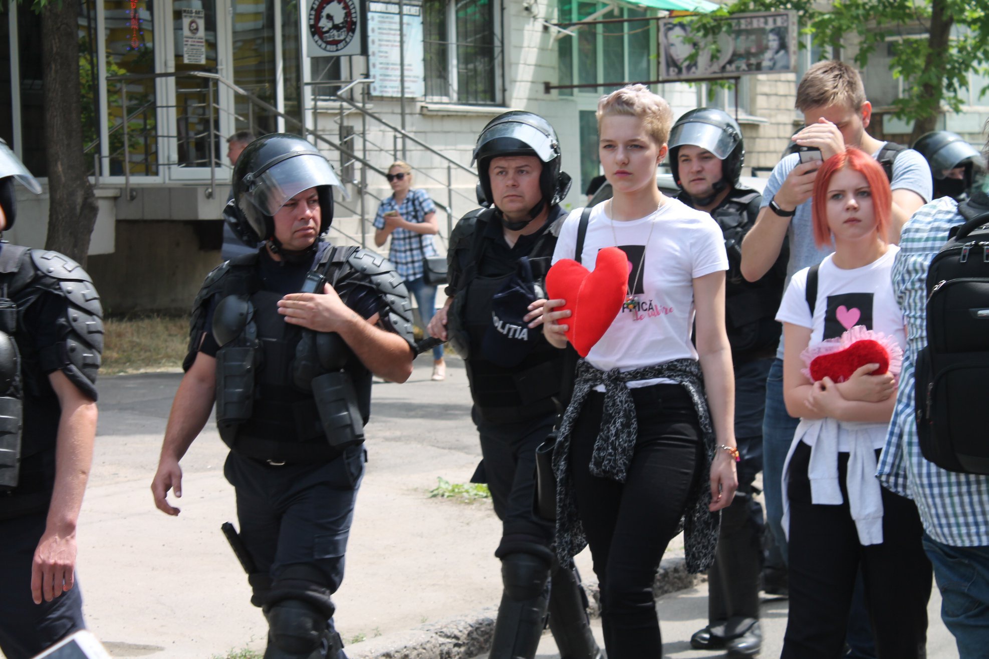 Изображение: Фотография Анны Плюсниной / Крупным планом изображены несколько полицейских и участни_ц акции. Последние несут в руках сердца.